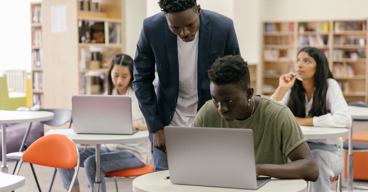 Teacher assisting students with laptops in a modern classroom